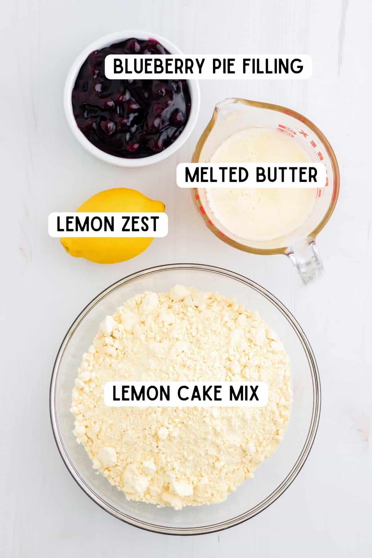 One lemon and bowls of blueberry pie filling, melted butter and lemon cake mix.