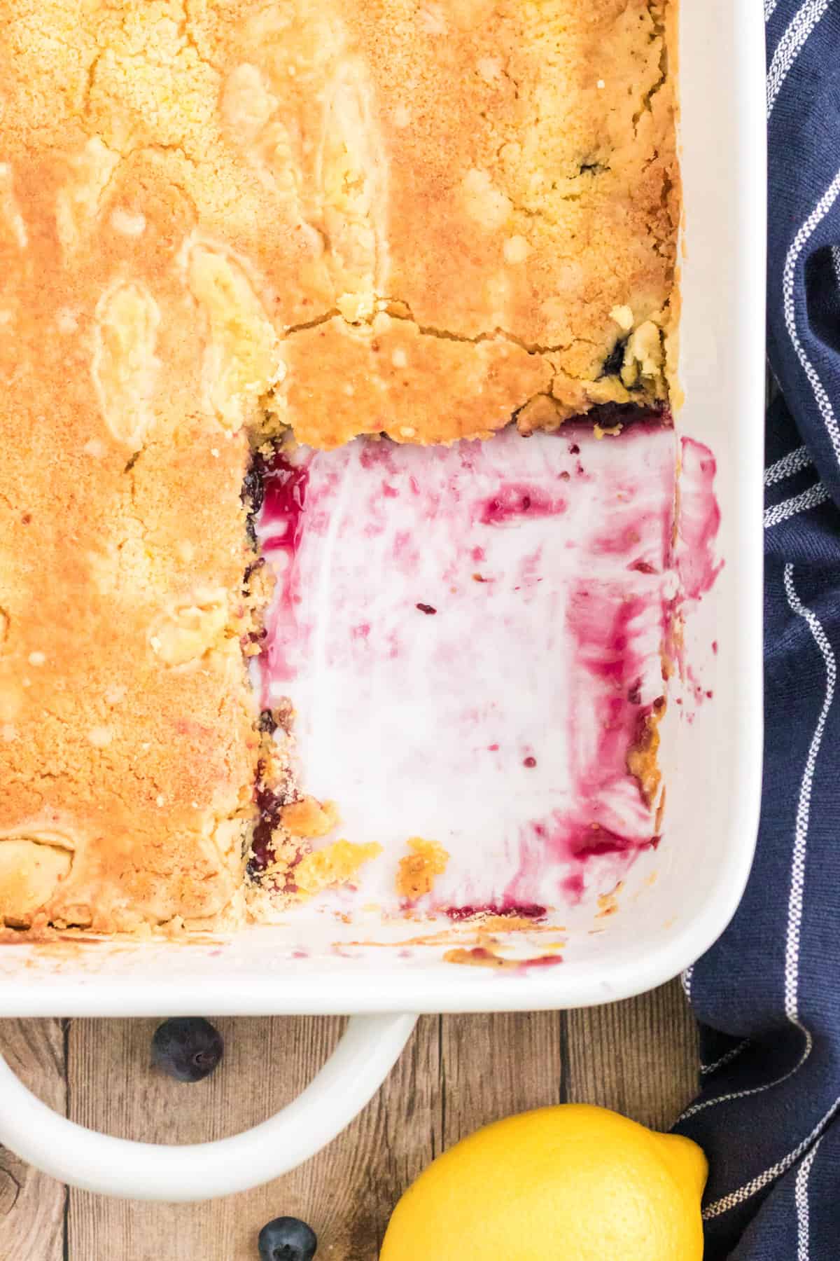 Lemon blueberry dump cake with a square serving missing from the corner.