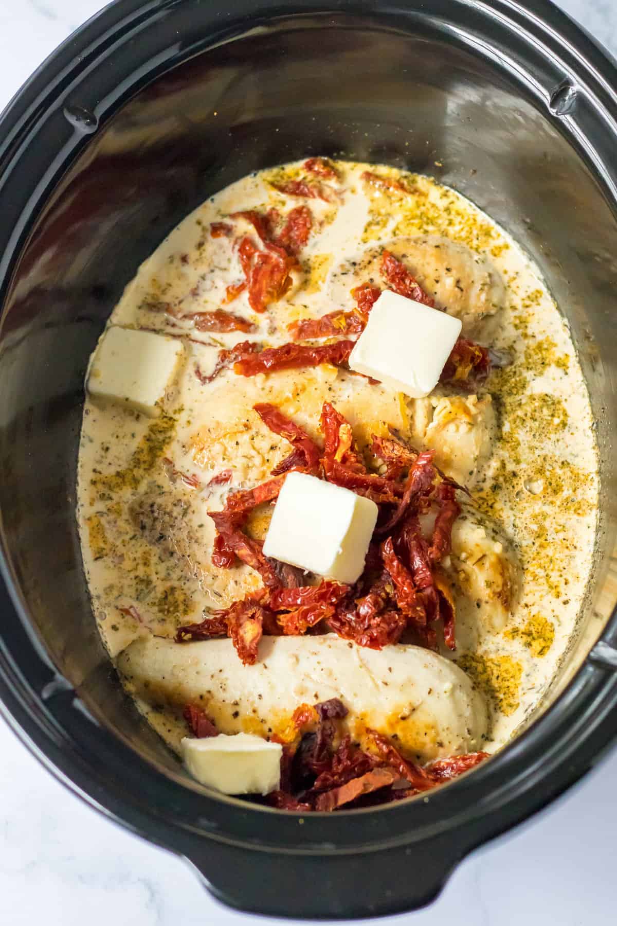 Chicken breasts with cream sauce, sun dried tomatoes, and butter in the crockpot.