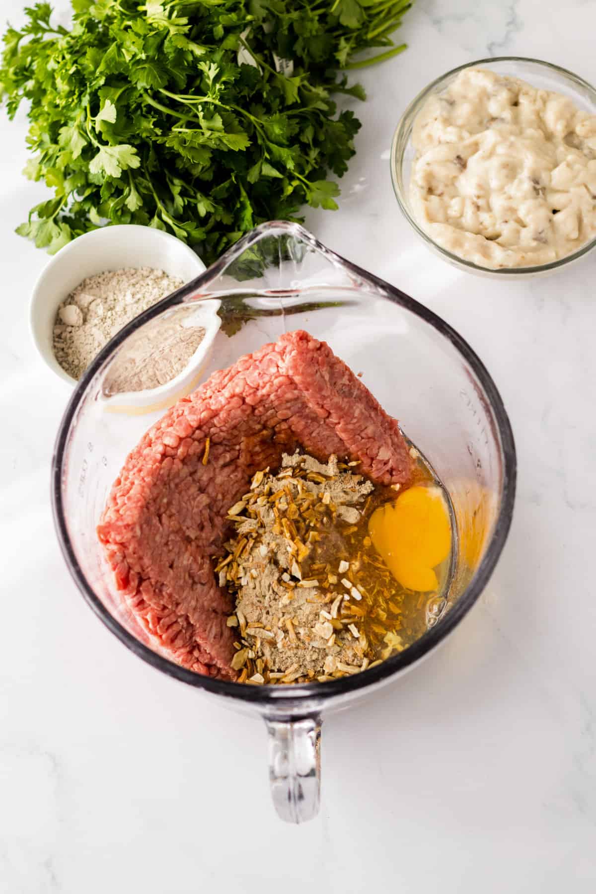 Ground beef, onion soup mix, egg, bread crumbs, worcestershire sauce, and steak seasoning in a large measuring cup.