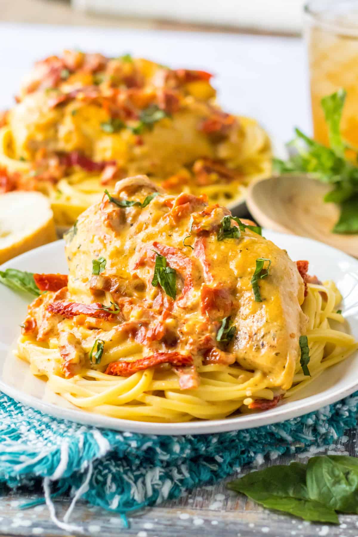 Slow cooker marry me chicken breasts with creamy sun-dried tomato sauce and fresh basil over spaghetti.