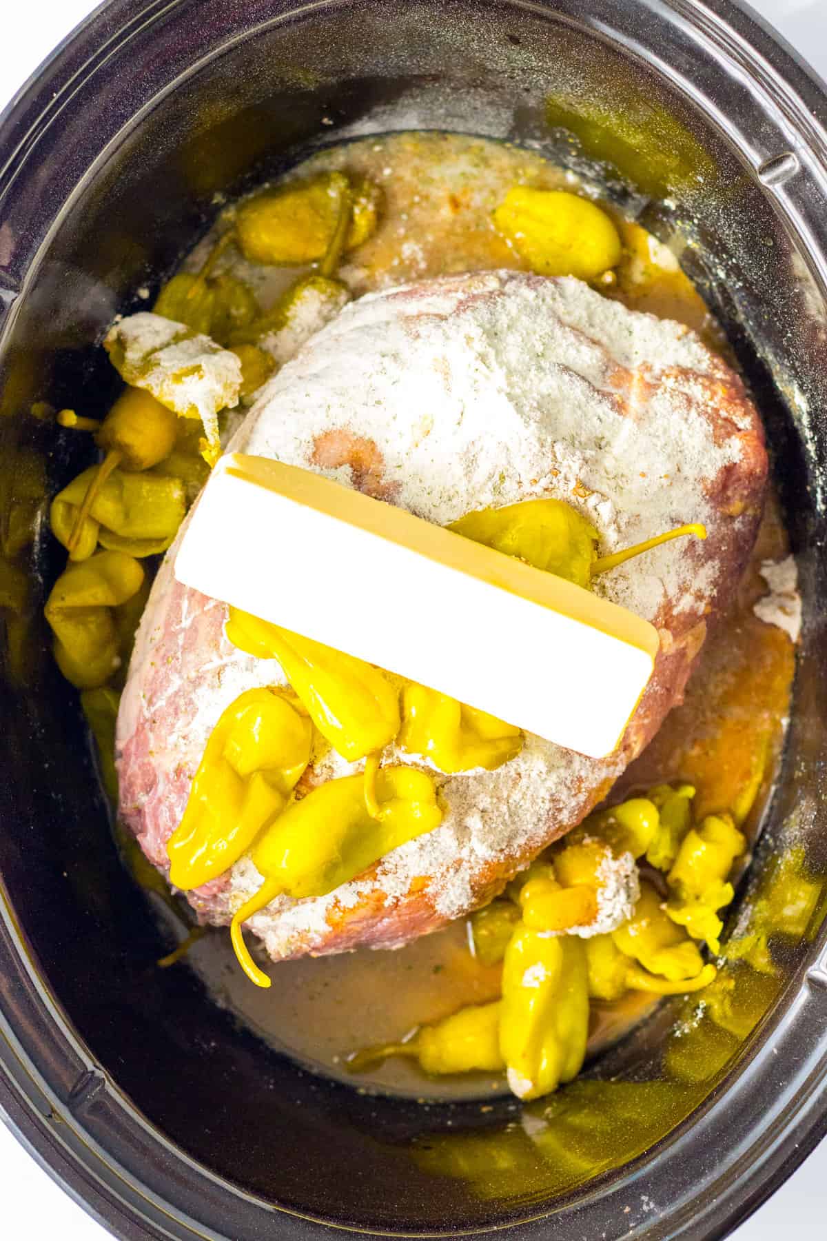 Roast in crockpot topped with seasonings, peppers, and stick of butter.