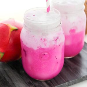 Copycat Starbucks Dragon Drink with vibrant pink mango dragonfruit refresher drink in mason jar topped with coconut milk.