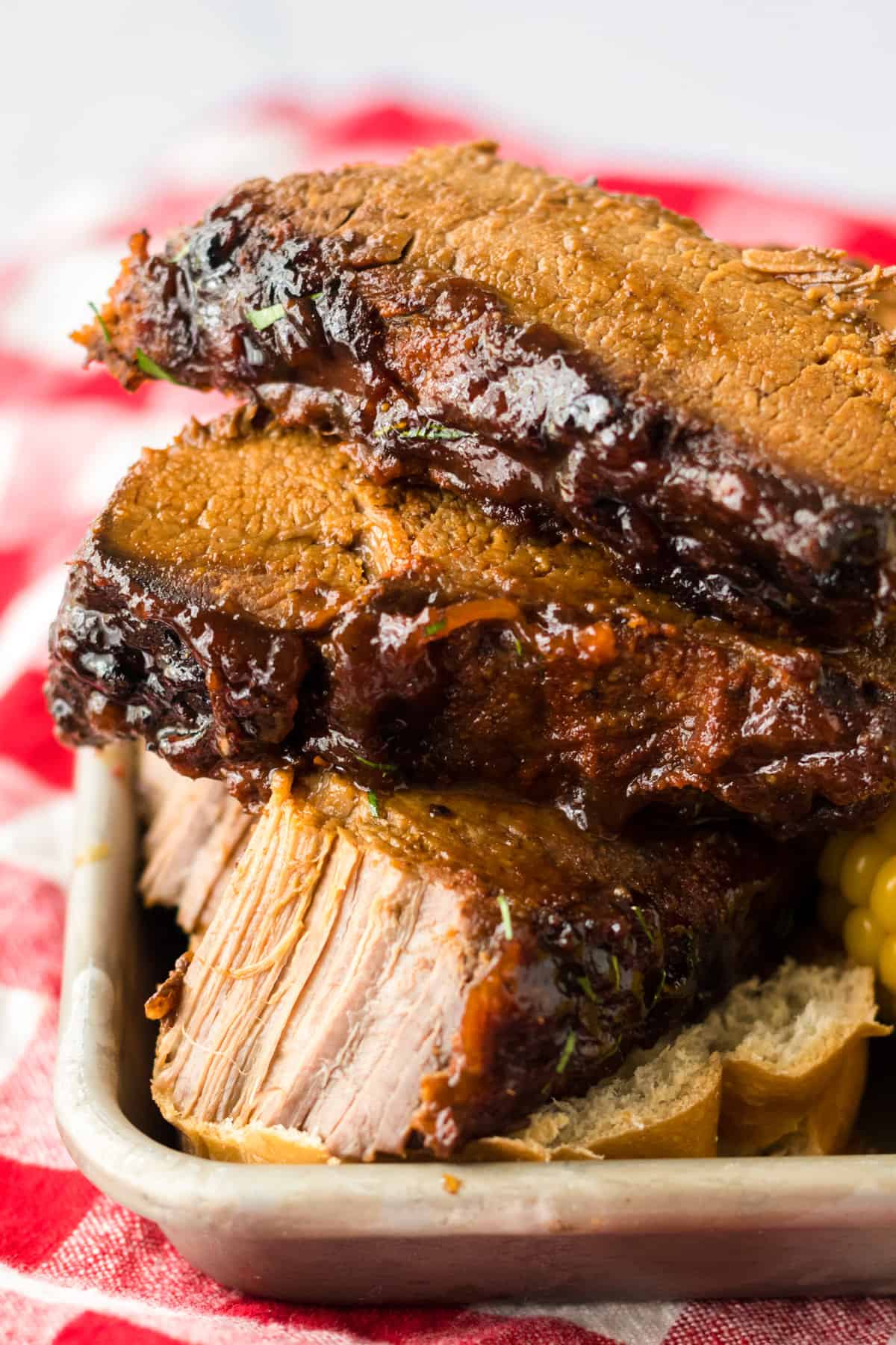 Pieces of slow cooker bbq brisket on tray with the bottom piece cut to show tender meat inside.