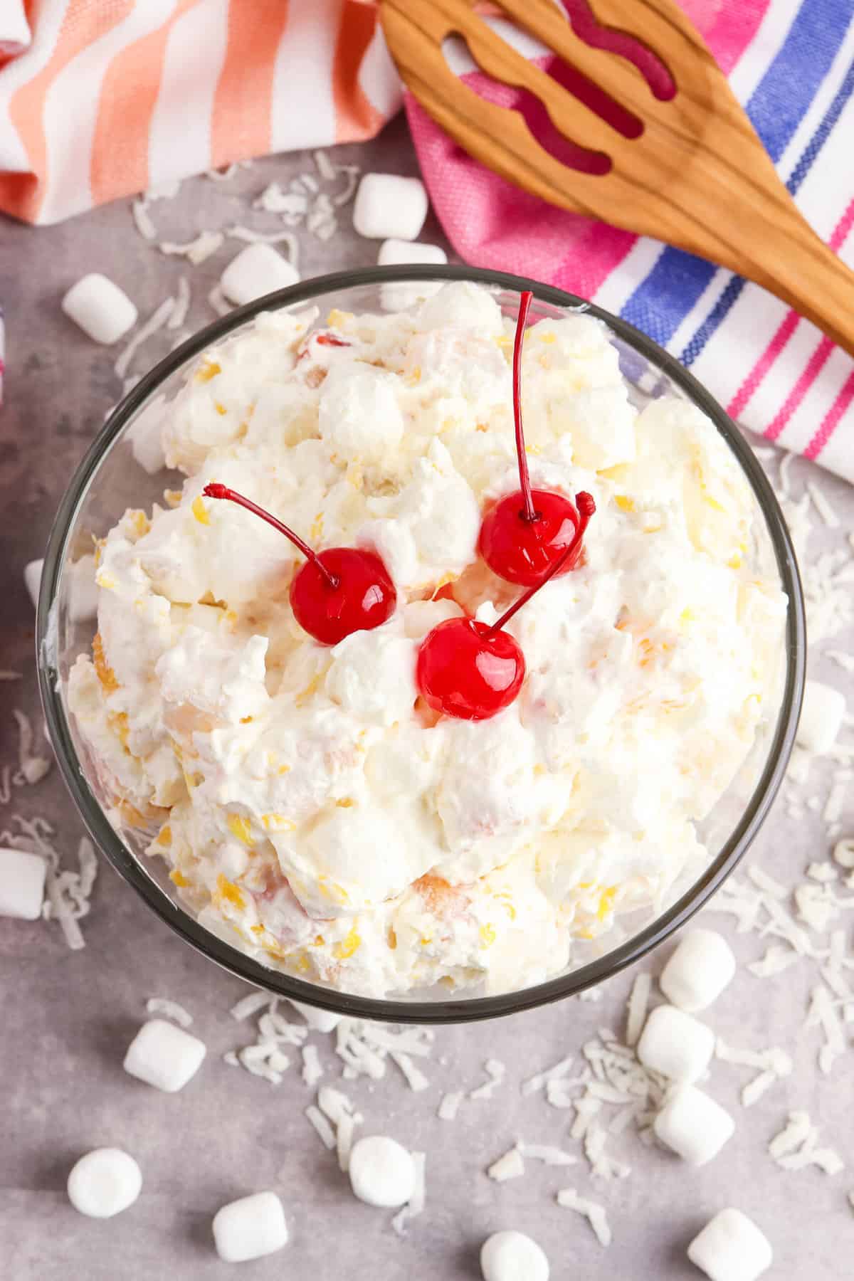 Overhead image of the fluffy salad in a serving bowl surrounded by coconut flakes and mini marshmallows.