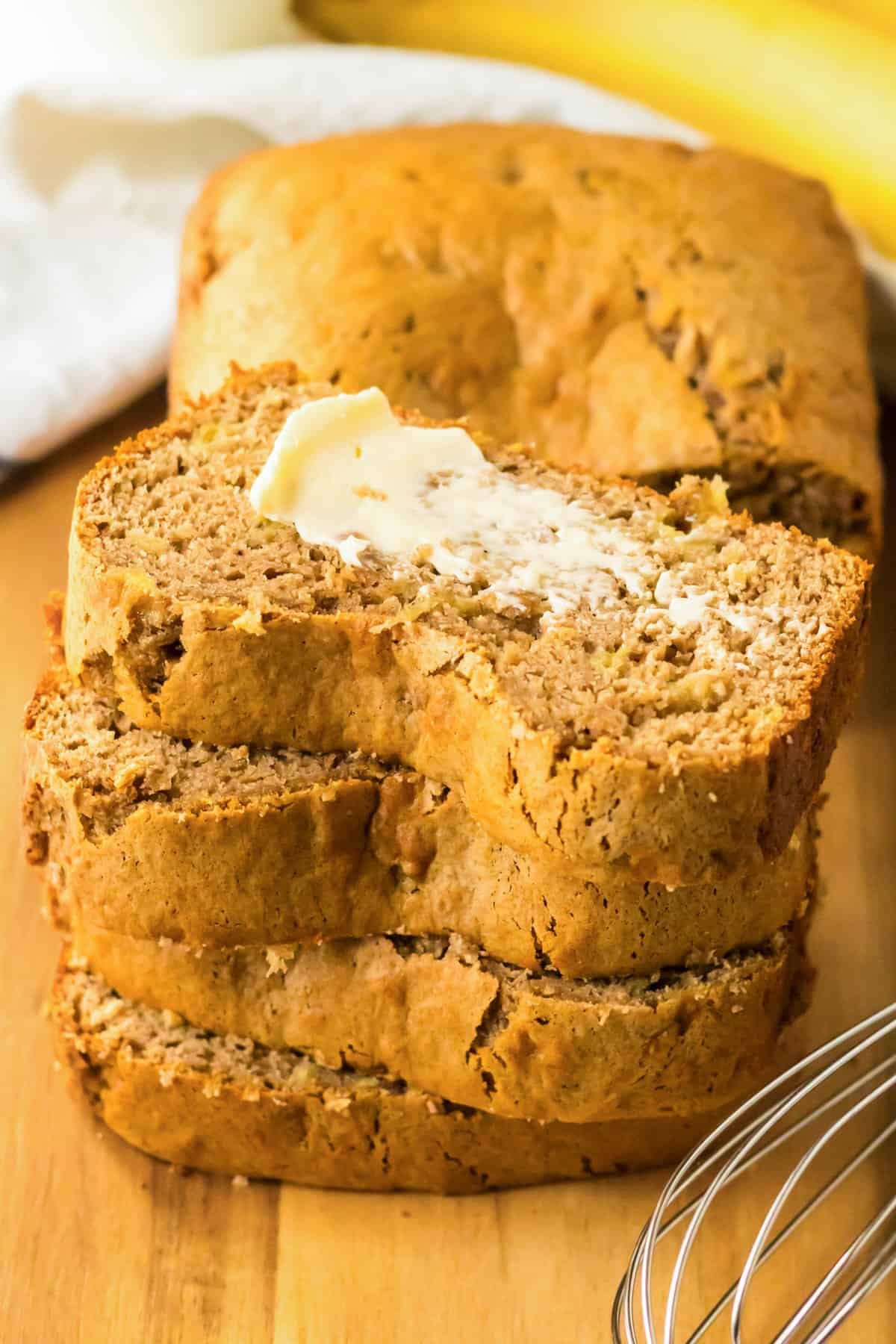 Stack of sliced easy cake mix banana bread, the top slice with butter.