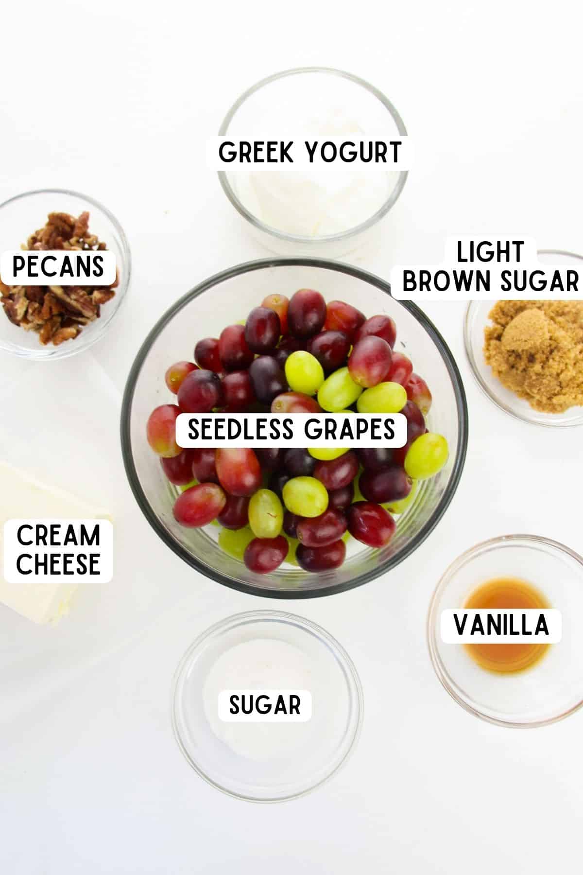 Bowls of light brown sugar, red and green seedless grapes, cream cheese, vanilla extract, pecans, greek yogurt, and white sugar.