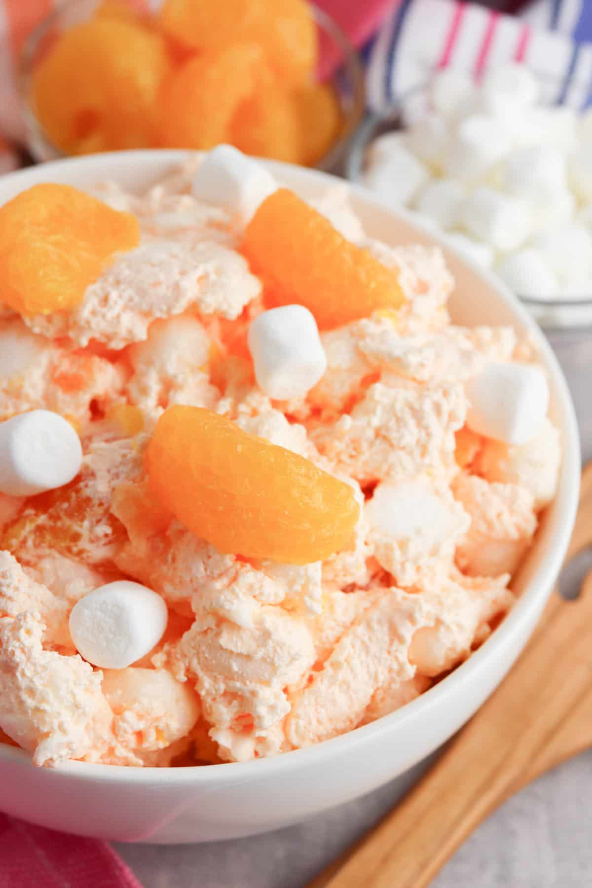 Bowl of orange creamsicle salad with wooden serving spoon.