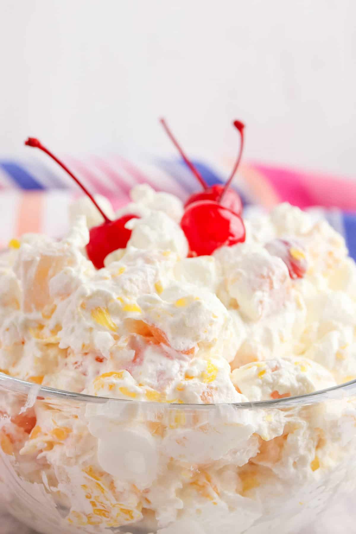 Close up of marshmallow ambrosia salad topped with 3 maraschino cherries.