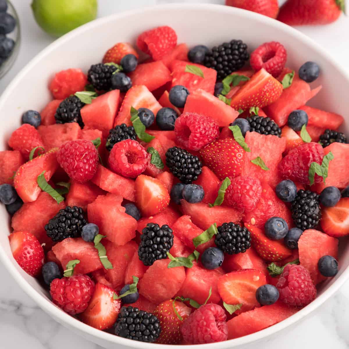 Watermelon fruit salad with fresh berries and thinly sliced mint leaves.