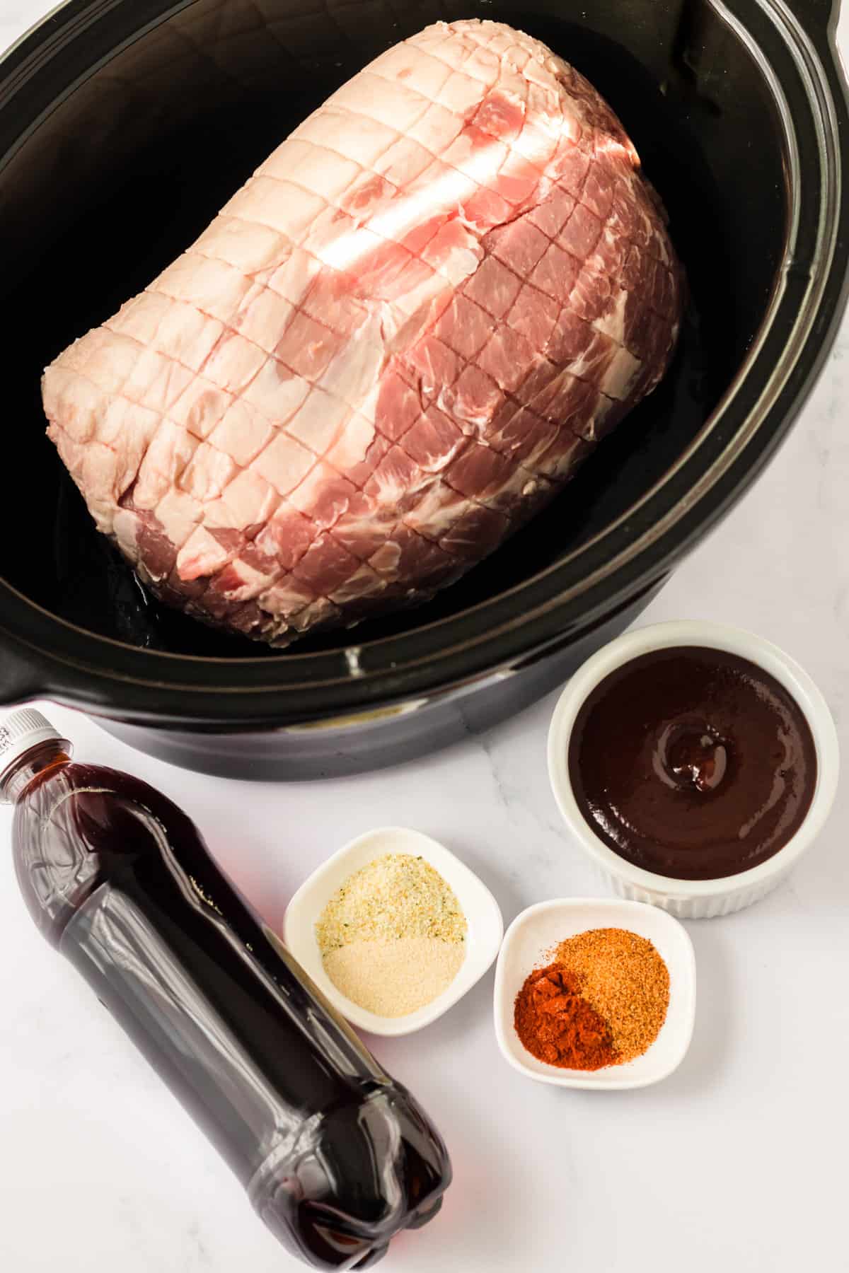 Pork roast in slow cooker with remaining ingredients beside it.
