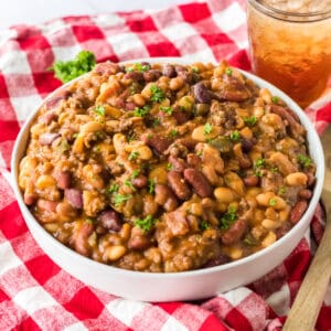 Slow cooker cowboy beans garnished with parsley and served in a large white bowl.