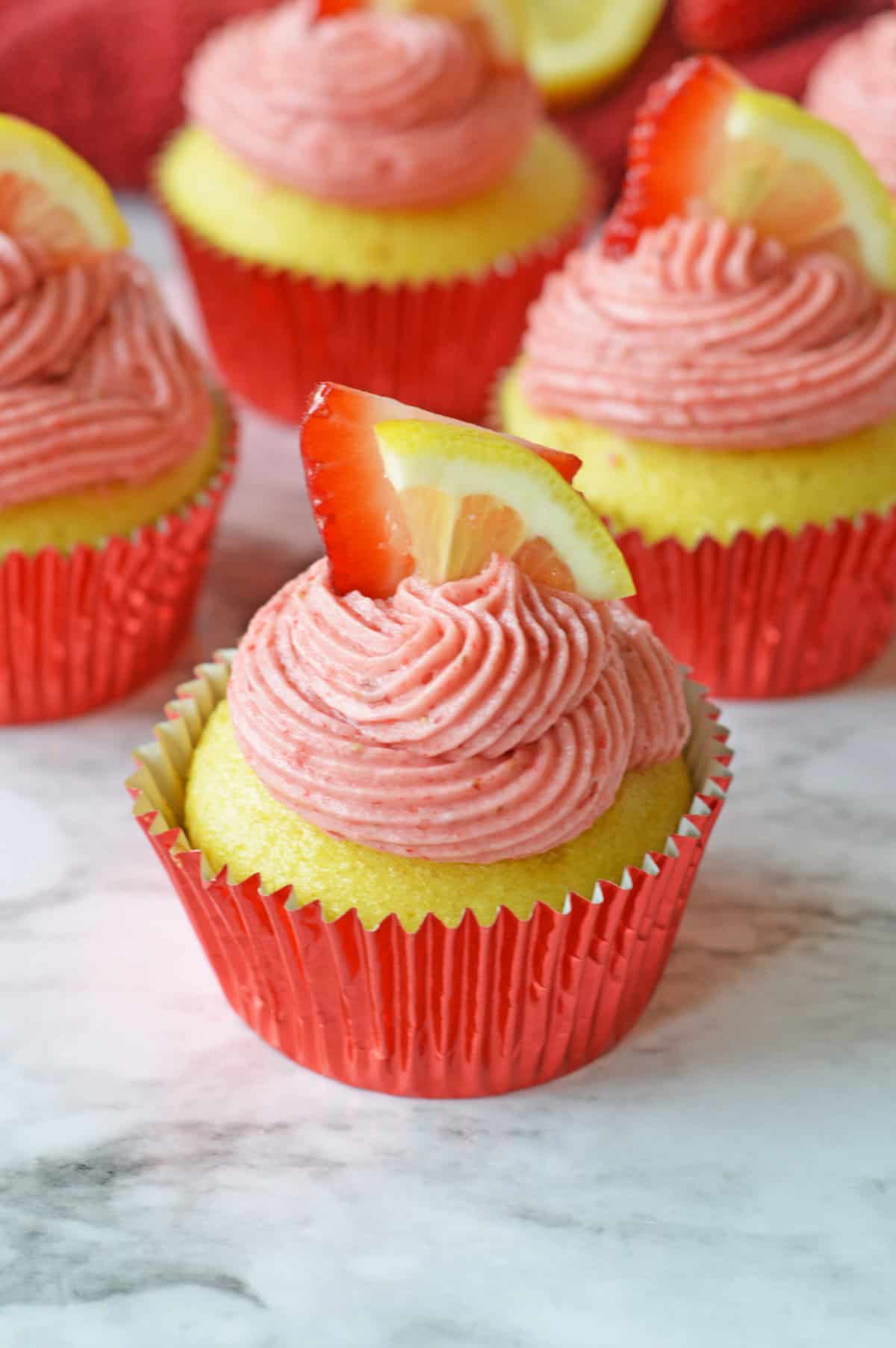 Strawberry lemonade cupcakes garnished with fresh lemon and strawberries.