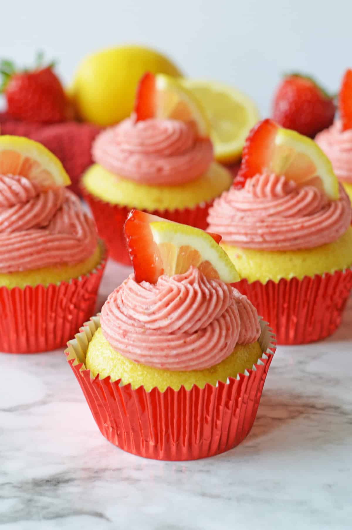 Strawberry lemonade cupcakes from cake mix with a homemade strawberry lemon frosting and finished with fresh lemon and strawberry slices.
