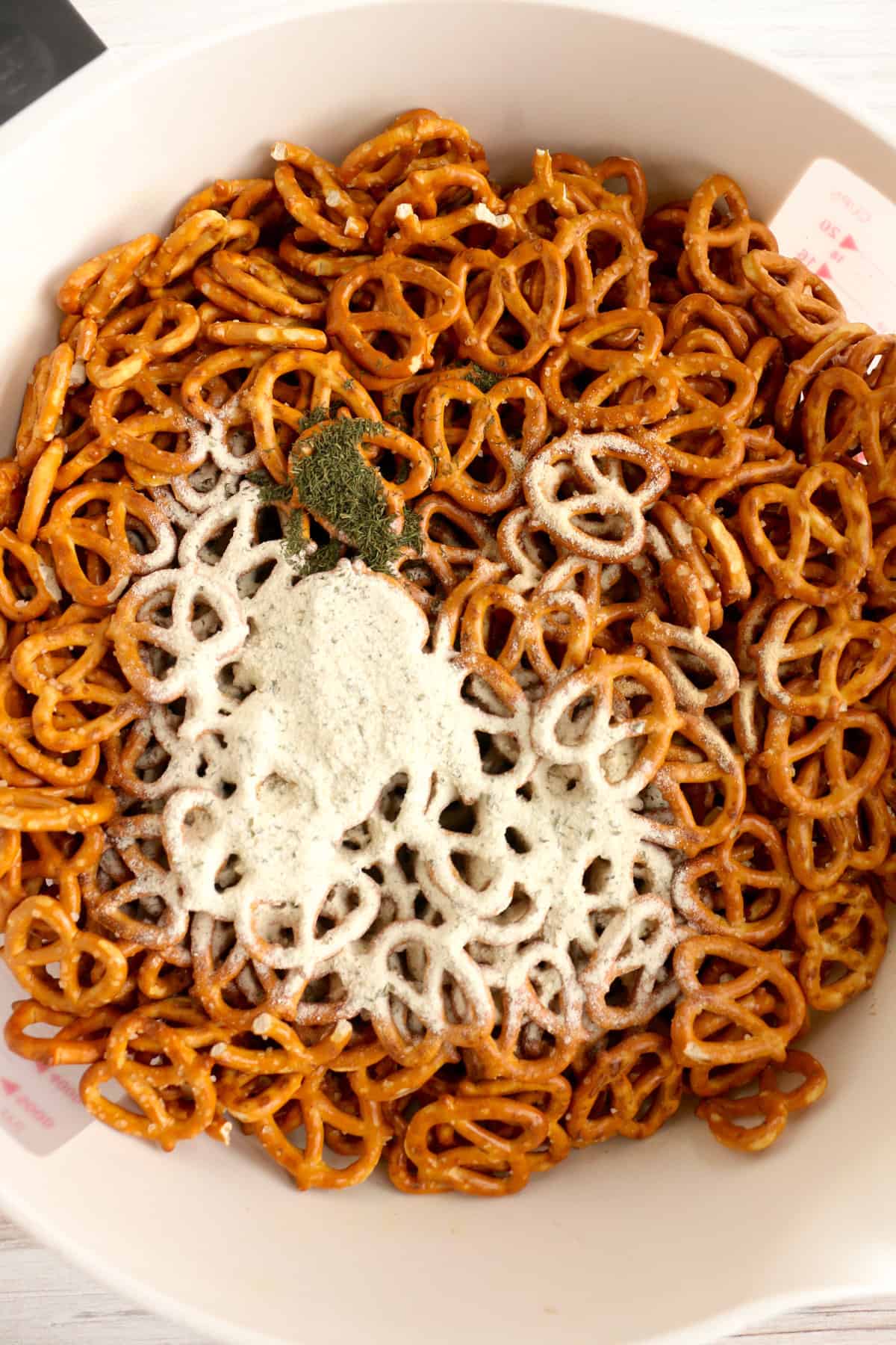 Ranch mix and other seasonings sprinkled on top over pretzel twists in a large bowl.