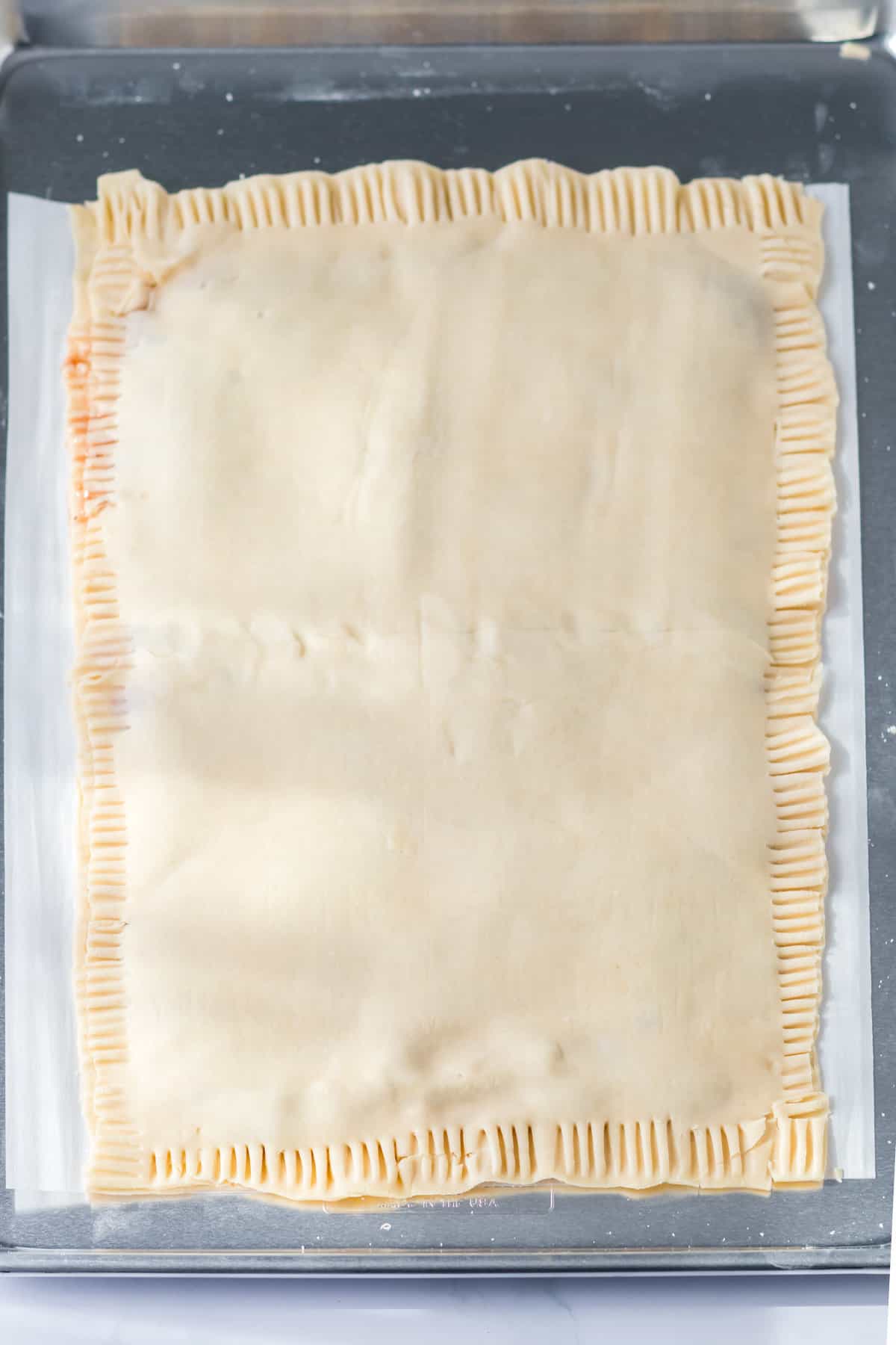 Top layer of pie crust placed over bottom layer and edges crimped with fork.