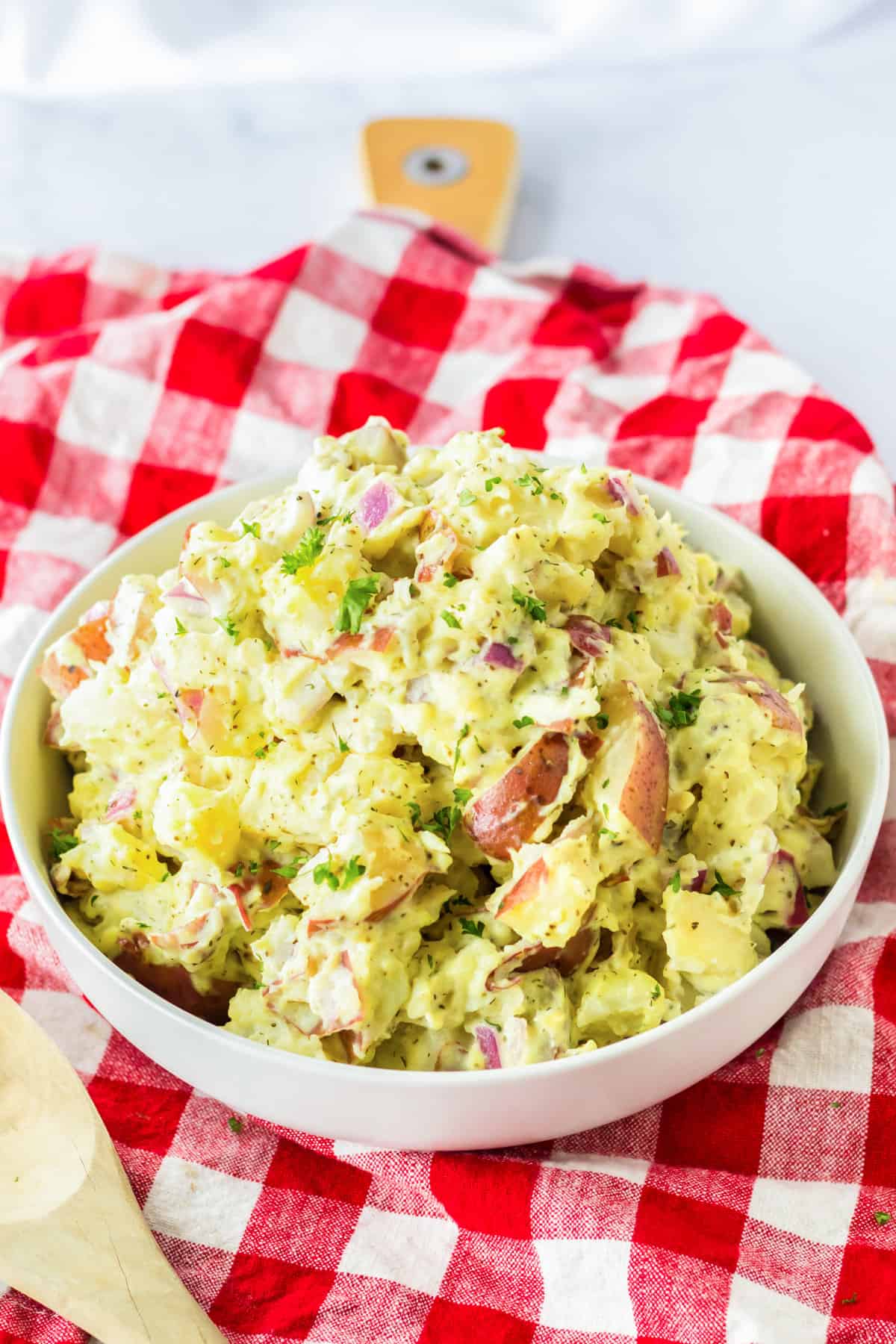 Bowl of red skinned potato salad on a red plaid linen.