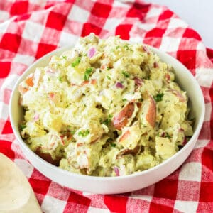 Bowl of red skinned potato salad on a red plaid linen.