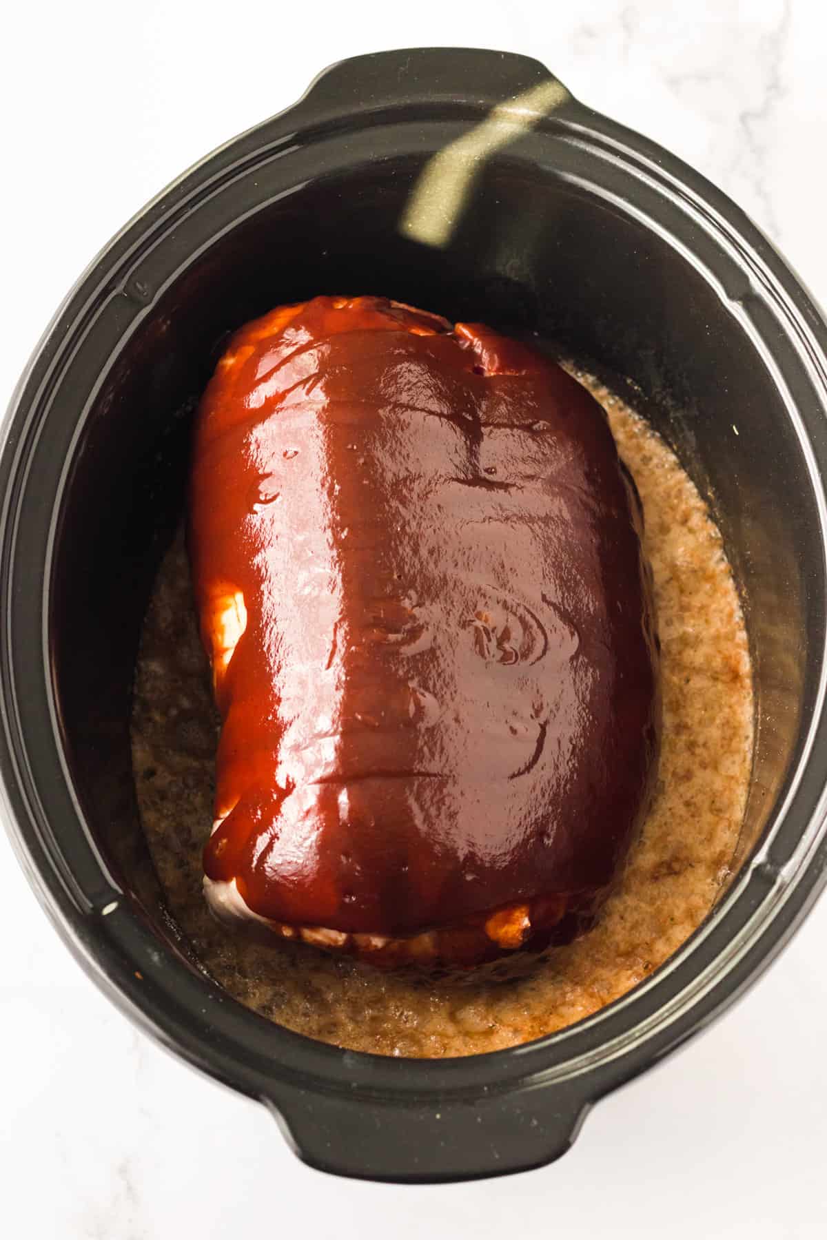Pork shoulder butt with BBQ sauce and root beer added to slow cooker.