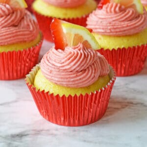 Strawberry lemonade cupcakes topped with fresh lemon and strawberries.