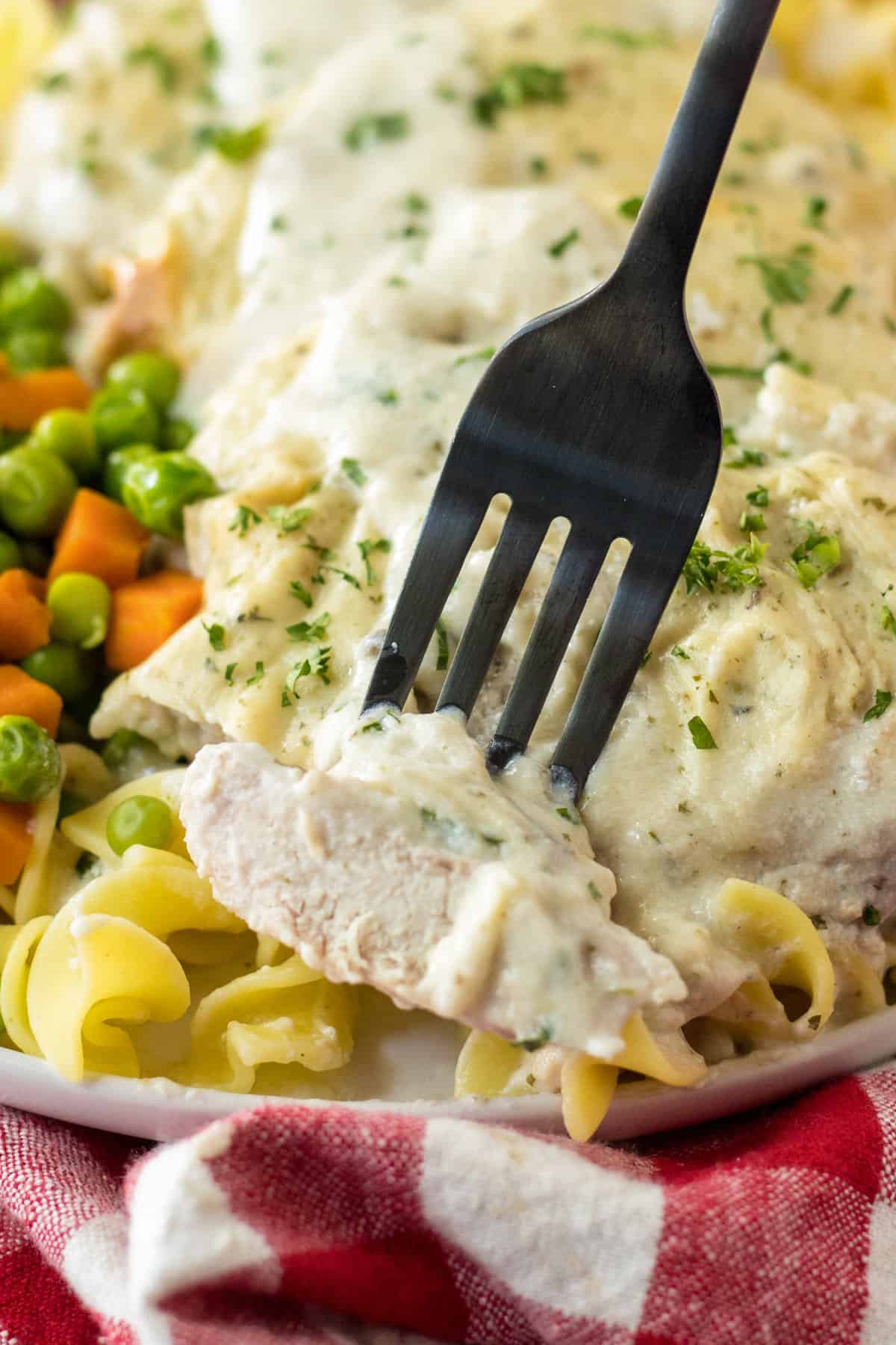 Form taking piece of baked pork chops with creamy sauce.