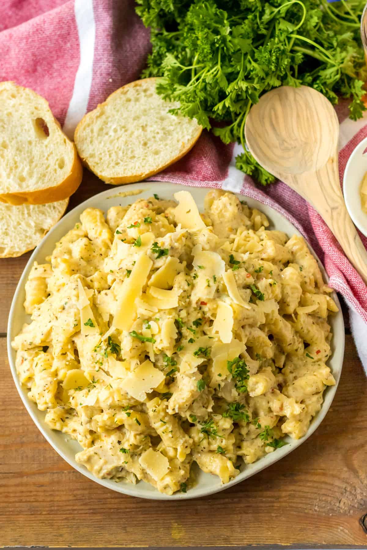 Slow Cooker Garlic Parmesan Chicken Pasta served garnished with fresh parsley and with slices or Italian bread on the side.