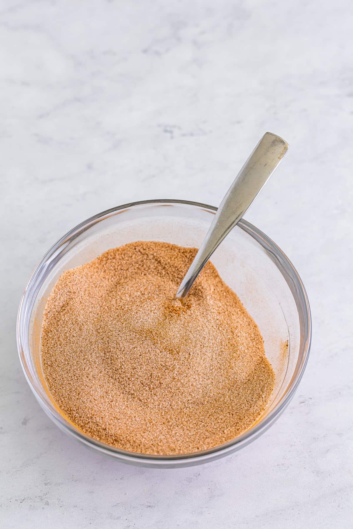 Cinnamon sugar in mixing bowl with spoon.