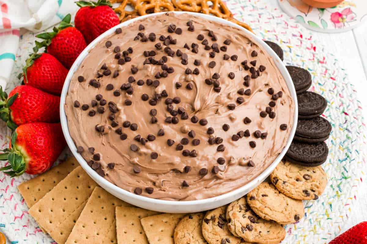 Bowl of brownie batter dip served with strawberries, cookies, and graham crackers for dipping.