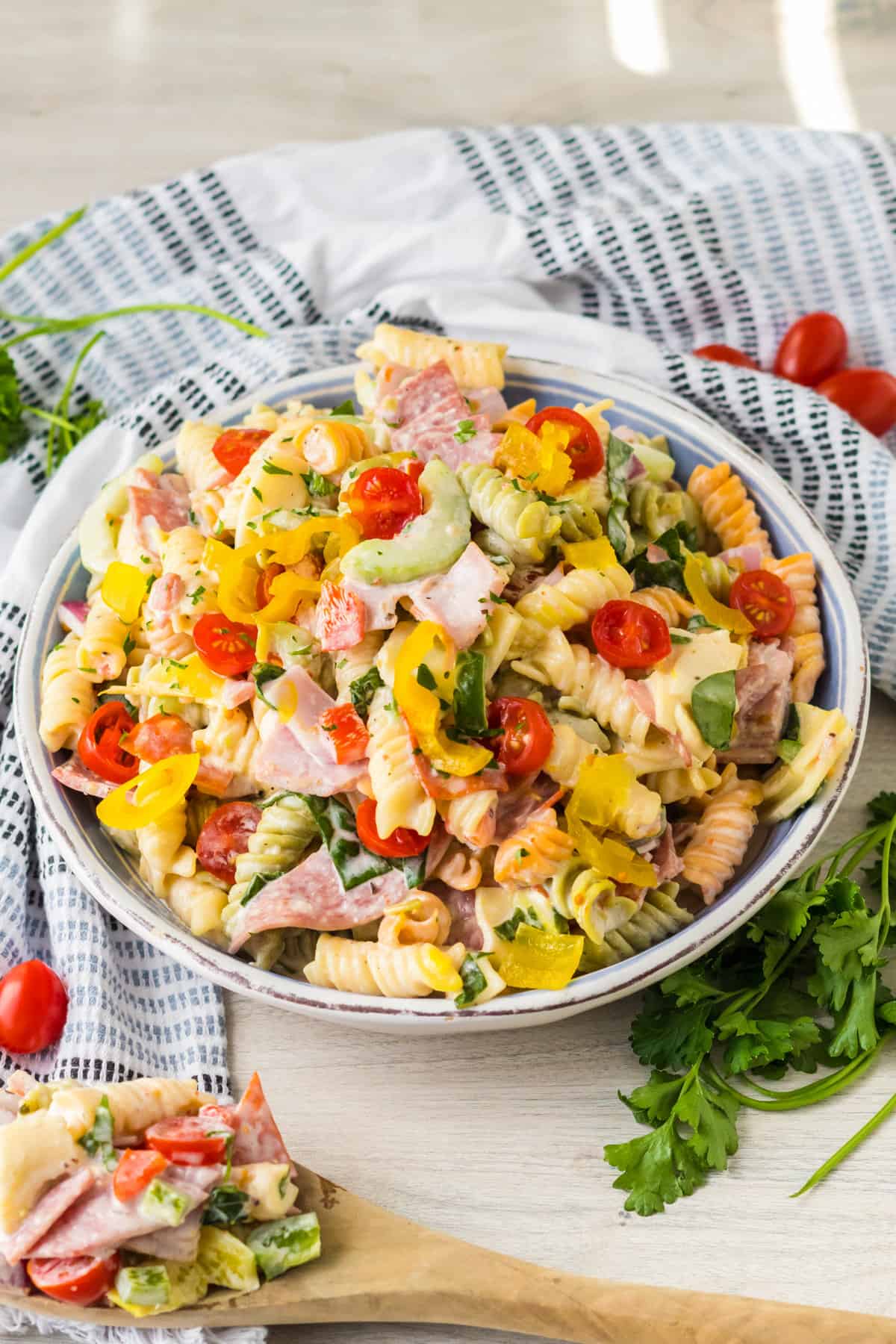 A colorful bowl of Italian pasta salad with rotini, fresh vegetables, and pasta salad dressing, surrounded by ingredients for tuna pasta salad and vegan pasta salad.