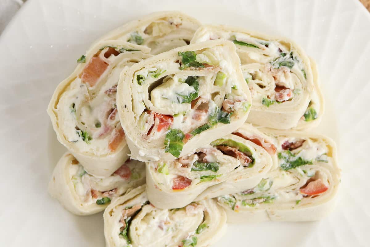 Top-down view of ranch pinwheels stacked on a white plate.