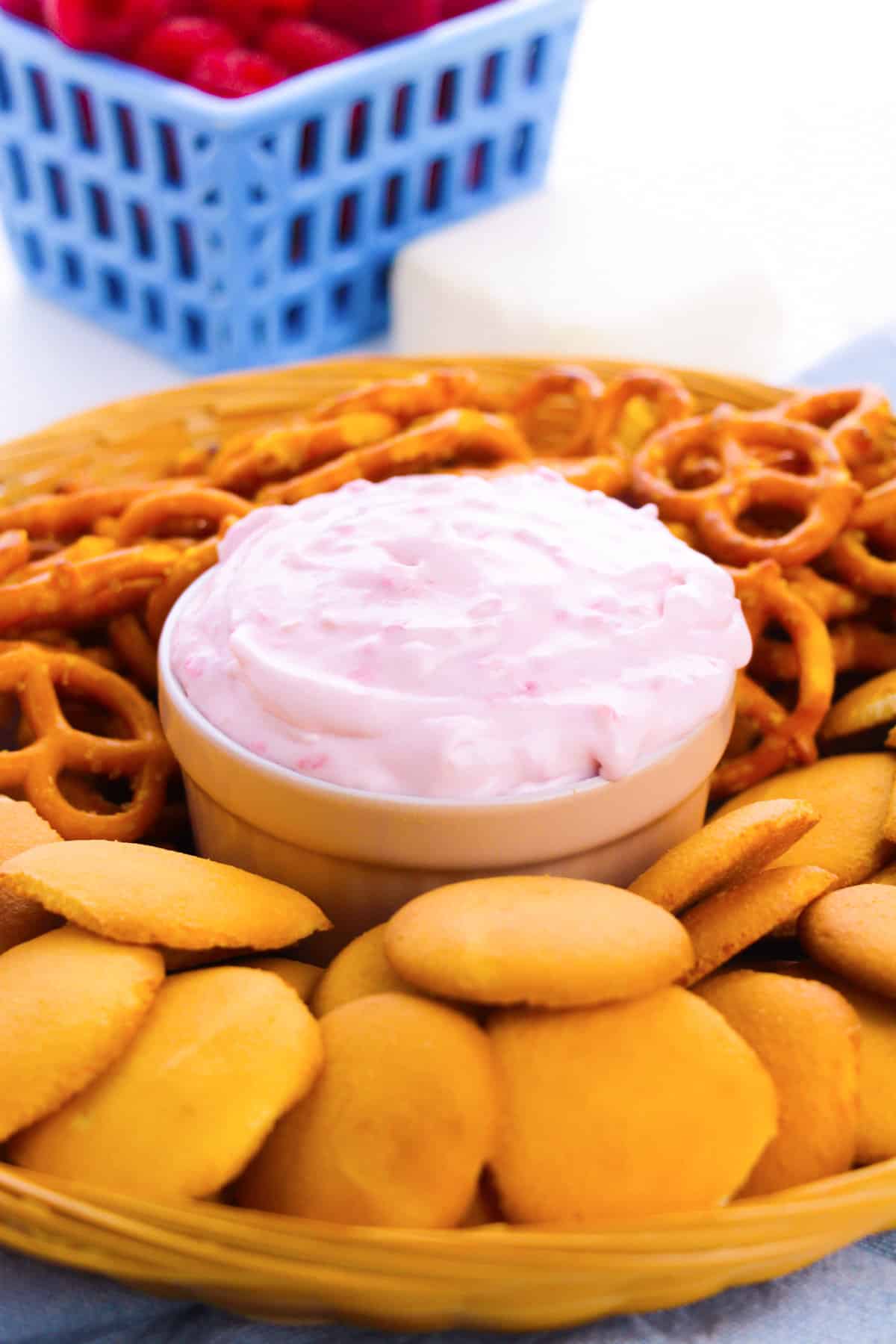 Raspberry cheesecake dip on a serving platter surrounded by nilla wafers and pretzels for dipping.