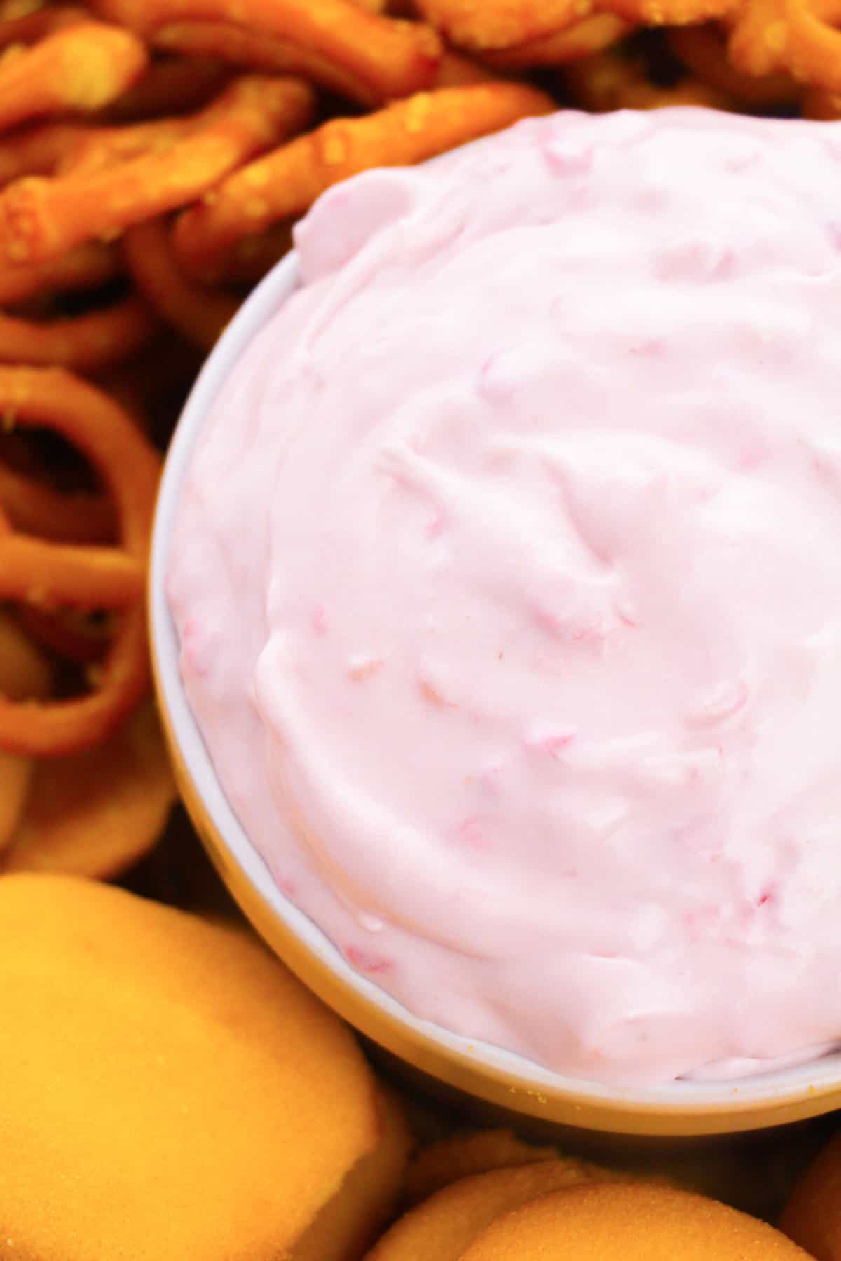 Raspberry cream cheese dip in a bowl served with vanilla wafers and pretzel twists.