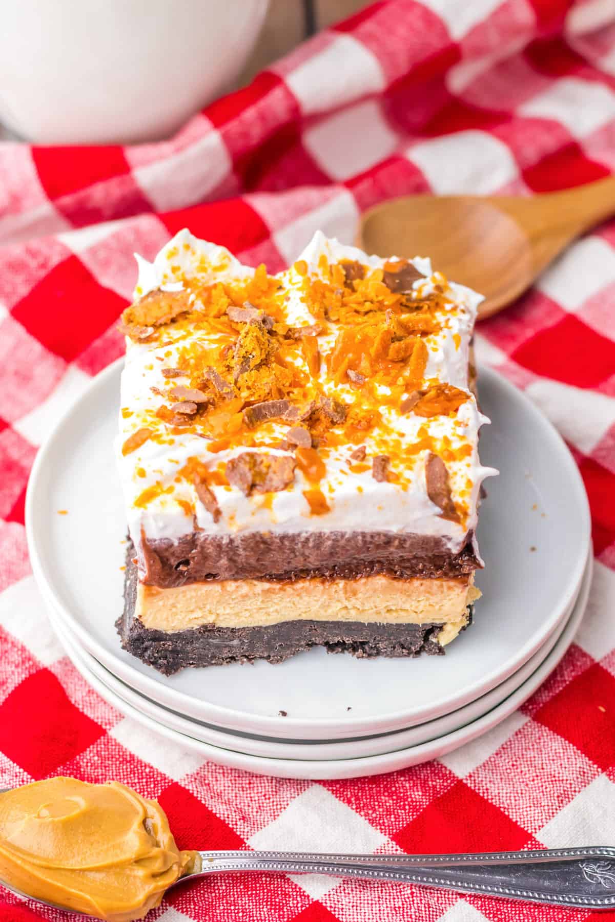 Butterfinger delight layered dessert topped with whipped topping and crushed butterfinger candy bars.