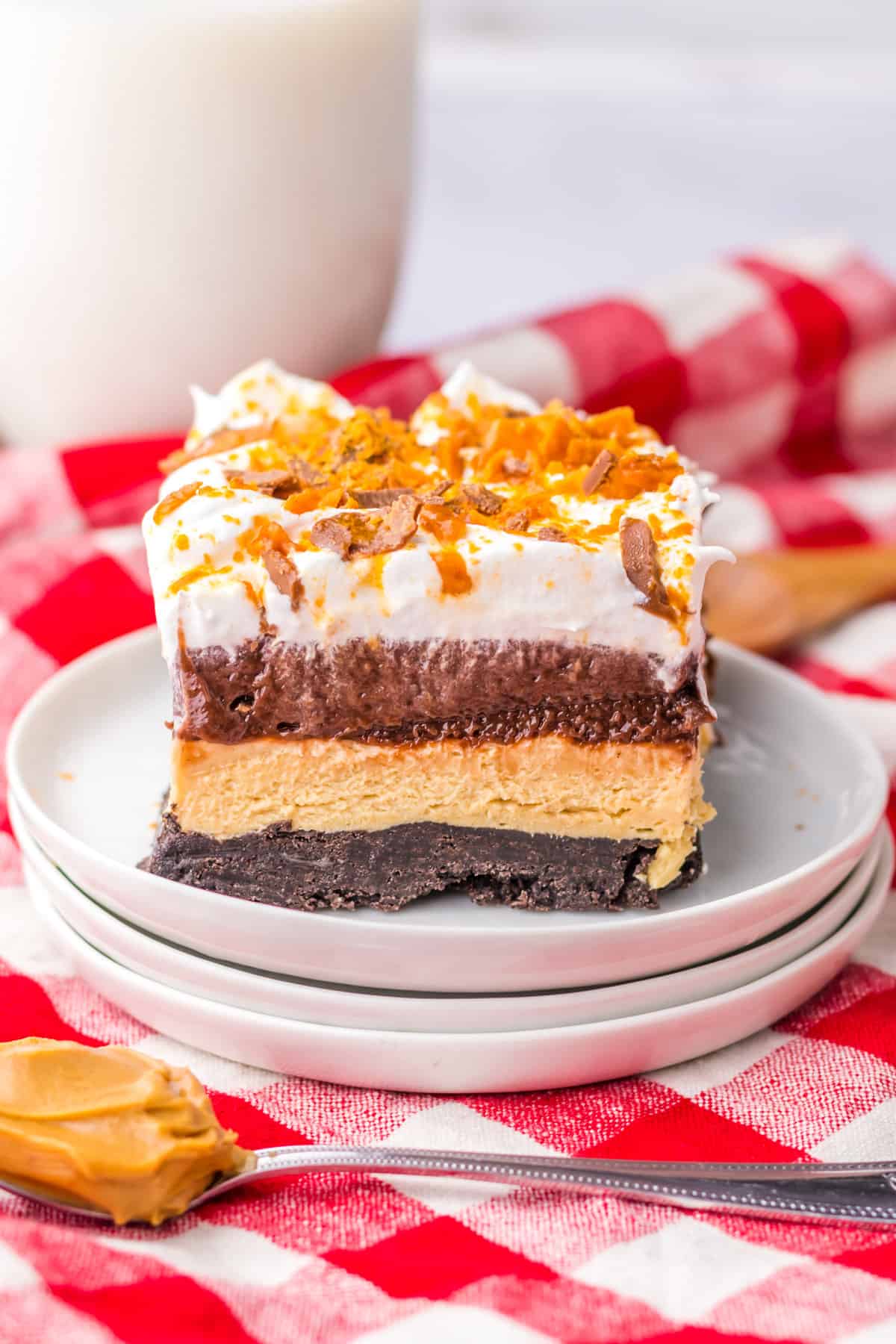 Butterfinger lush with an oreo cookie crust and layers of no bake peanut butter cheesecake, chocolate pudding, cool whip, and crushed butterfingers.