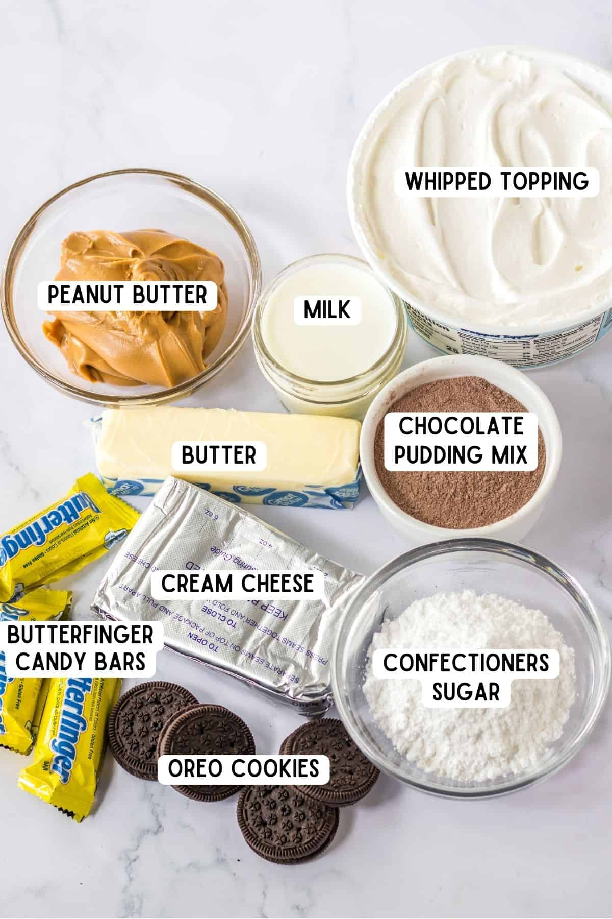 Tub of cool whip, stick of butter, glass of milk, block of cream cheese, mini butterfinger bars, oreo cookies, and bowls of: confectiners sugar, peanut butter, and instant chocolate pudding mix.