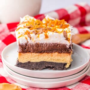 Butterfinger lush with an oreo cookie crust and layers of no bake peanut butter cheesecake, chocolate pudding, cool whip, and crushed butterfingers.