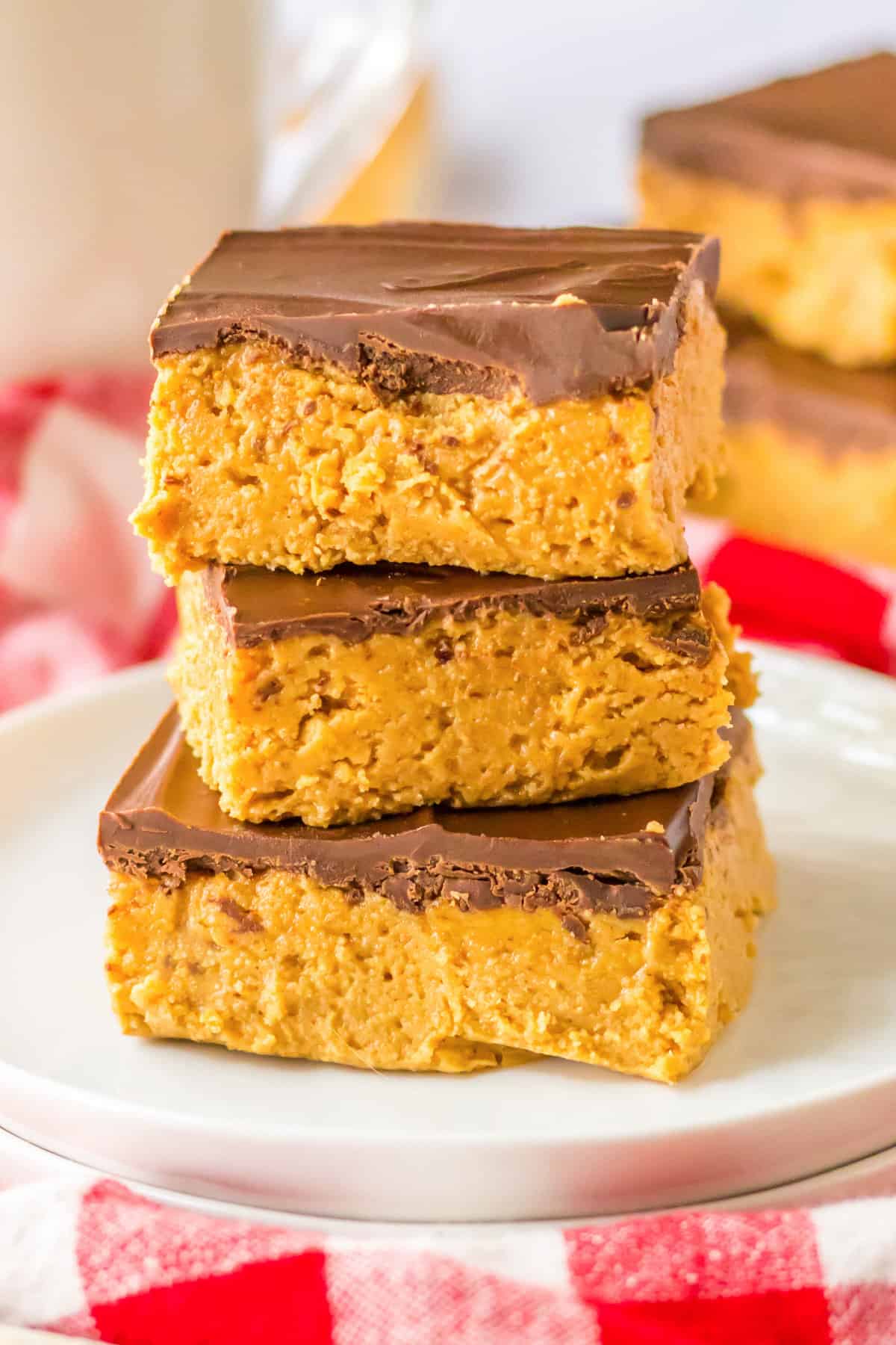 5 Ingredient no-bake chocolate peanut butter bars stacked on a white plate.