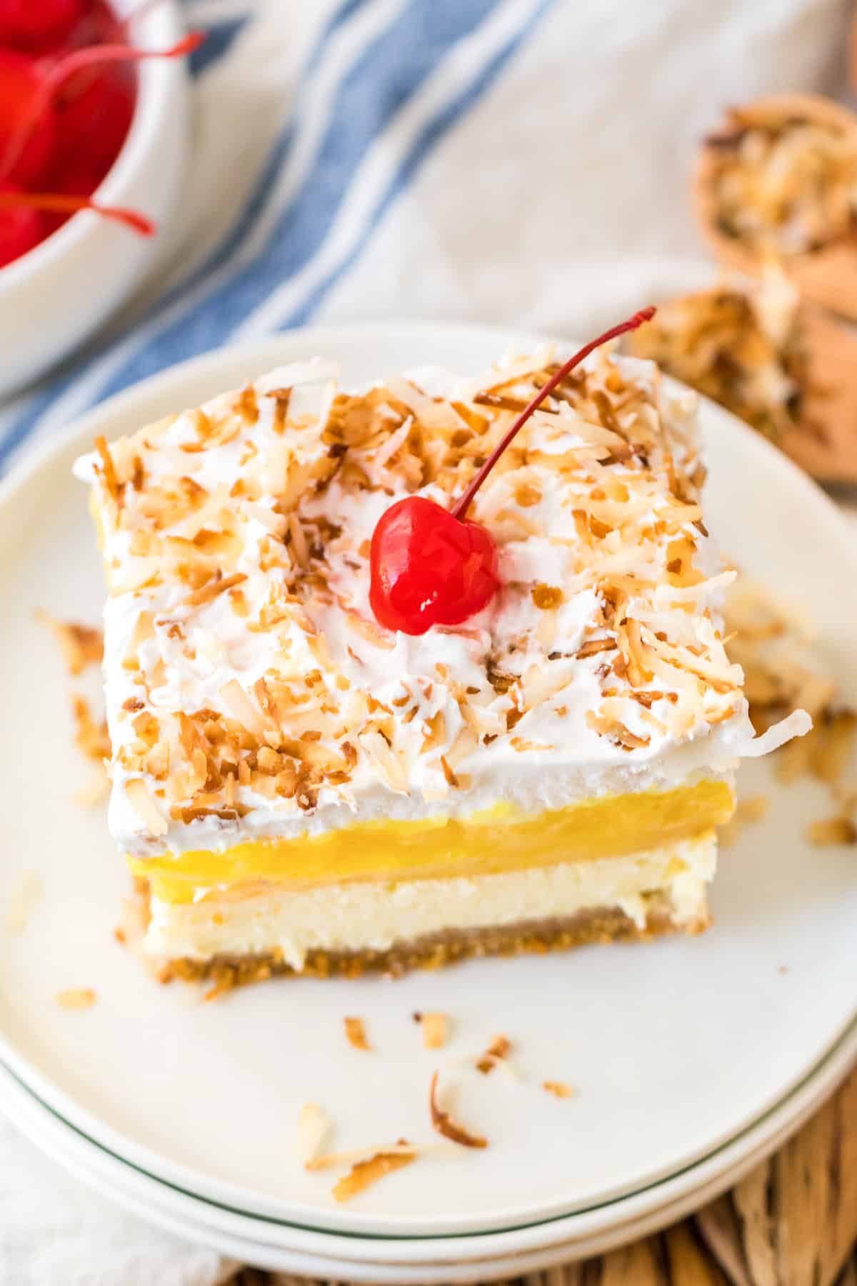 Pineapple Coconut Layered Dessert with layers of creamy pineapple filling, coconut cheesecake, and whipped topping on top of a buttery graham cracker crust.