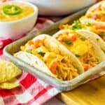 Slow cooker queso chicken tacos in flour tortillas on a serving tray.