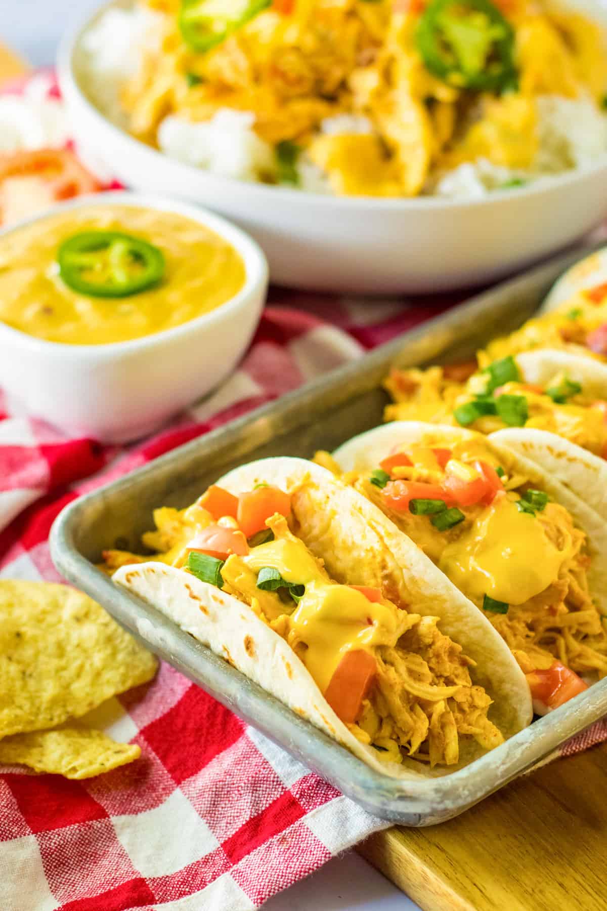 Slow cooker queso chicken tacos in flour tortillas on a serving tray.