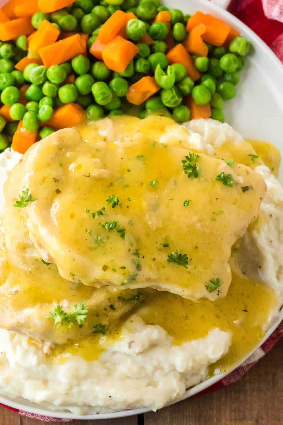 3 Ingredient crock pot pork chops with ranch dressing mix served over mashed potatoes with a side of veggies.