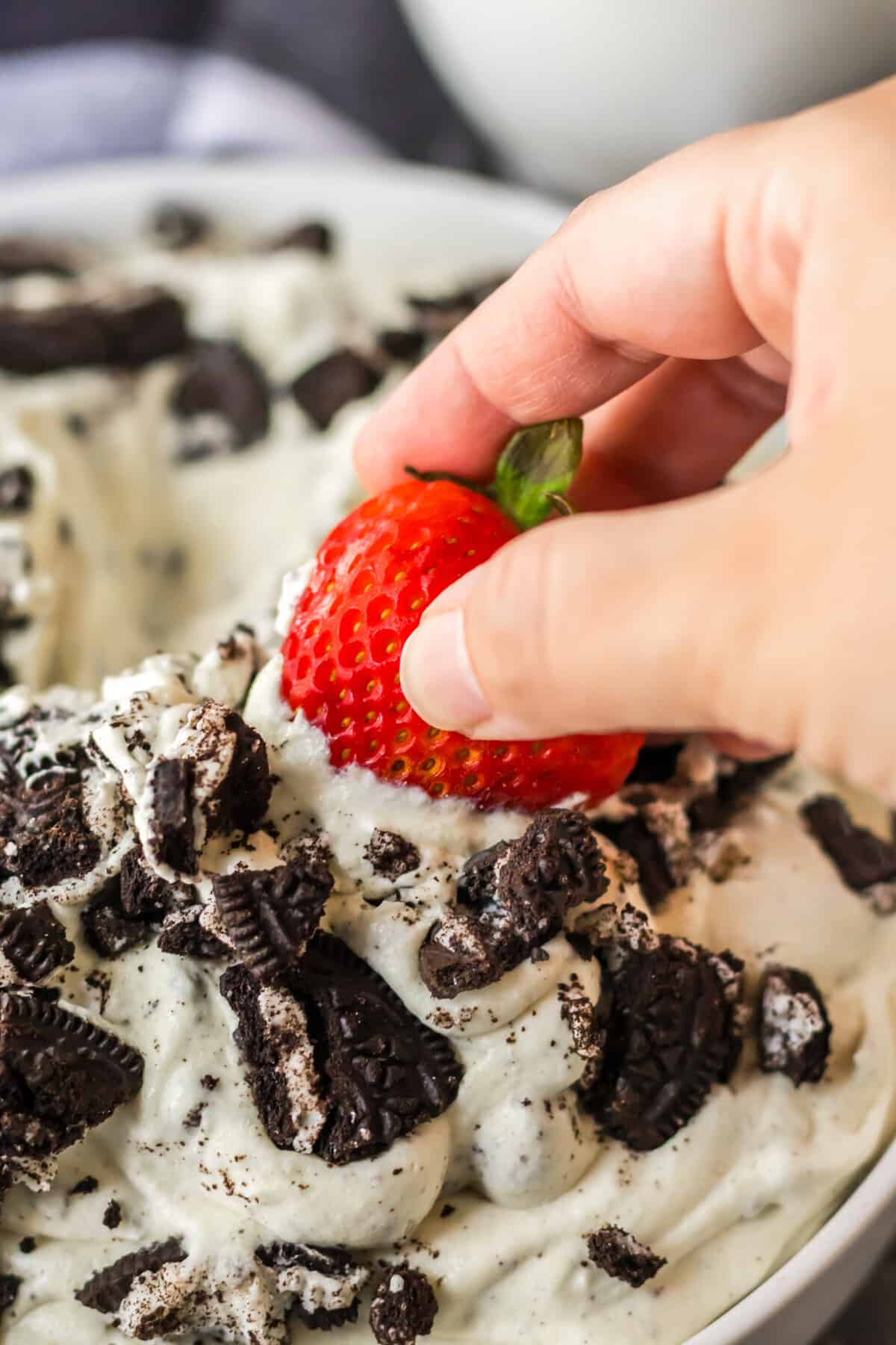 Fresh strawberry being dipped in oreo fluff.