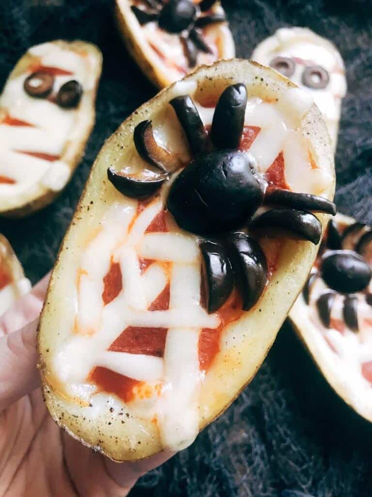 Potato Skins topped with a mozzarella cheese spider web and olive spider.