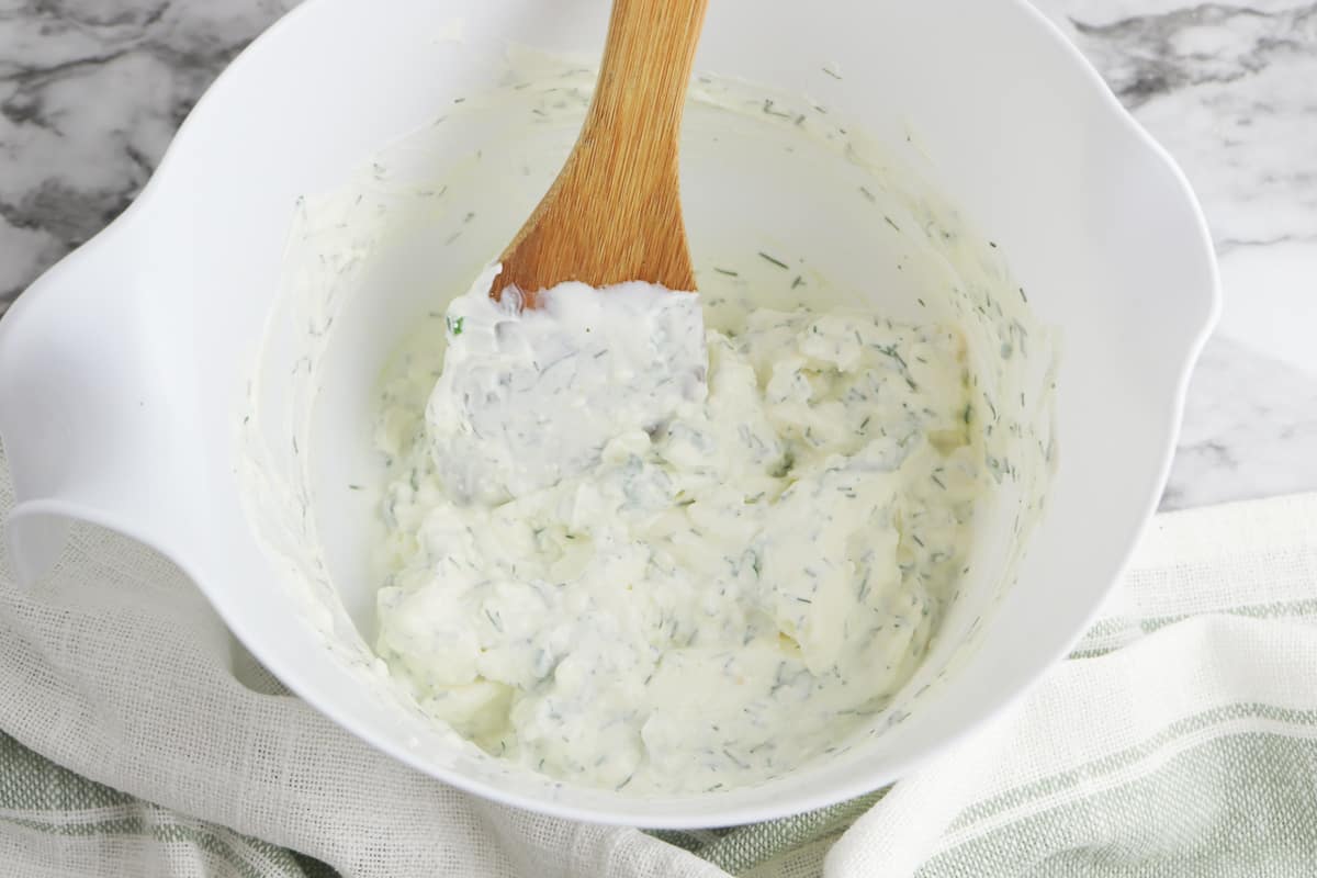 Dill dip in a bowl with a wooden spoon.