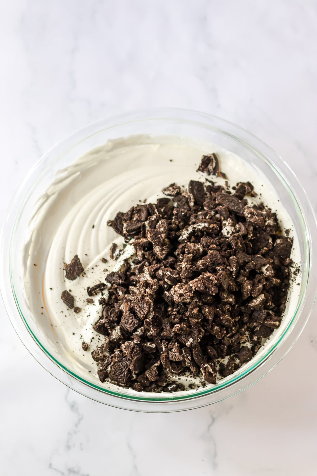Crushed Oreo Cookies added to the mixing bowl with the creamy pudding and cool whip mixture.