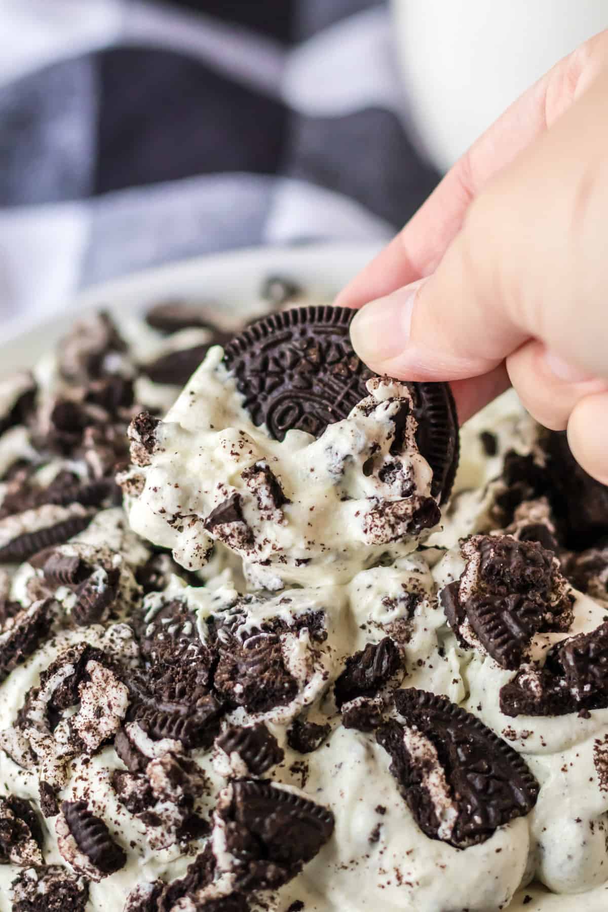 Oreo cookie being dipped in bowl of oreo fluff dip.