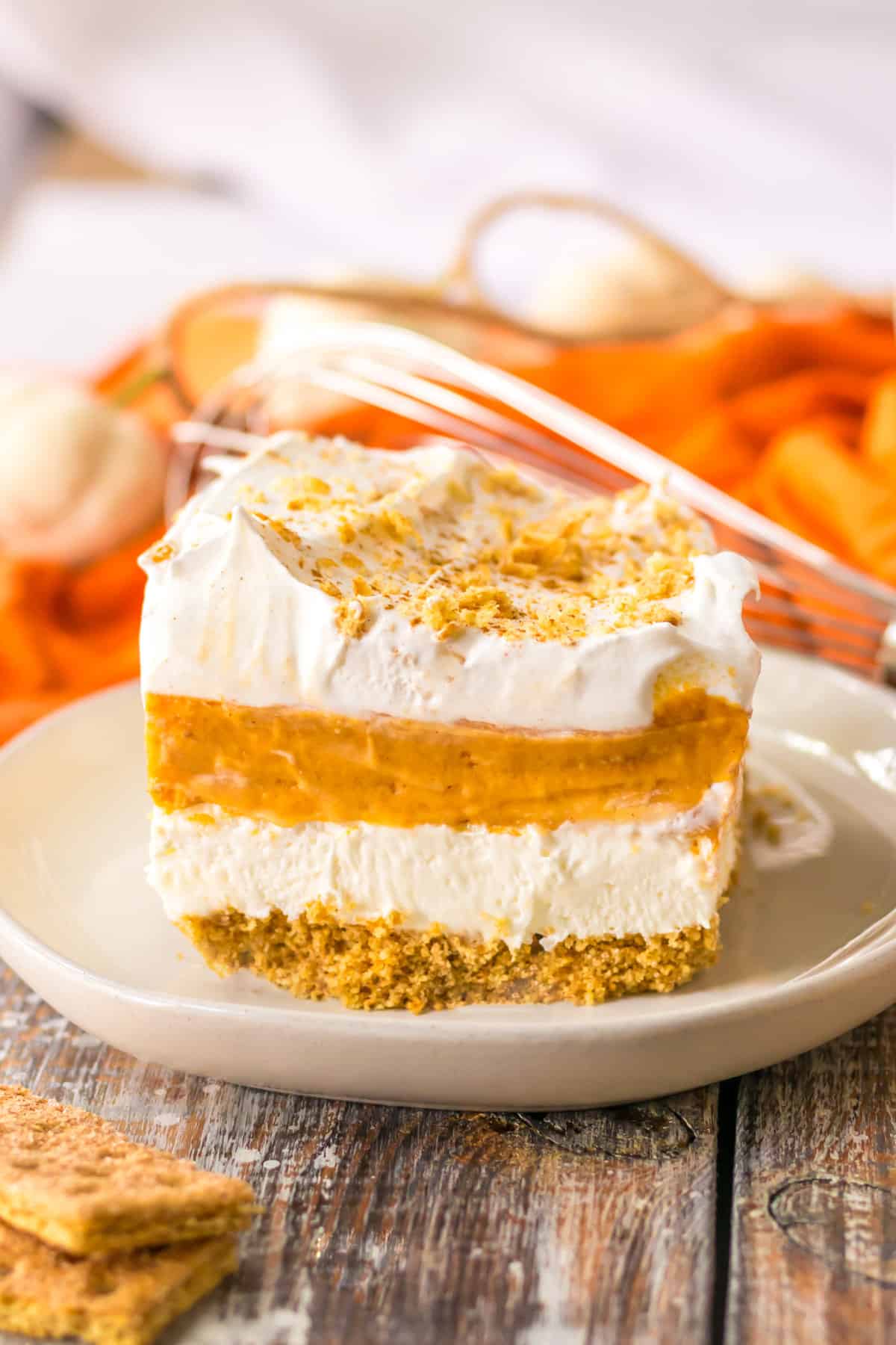 No bake pumpkin lush layered dessert with a graham cracker crust, sweetened cream cheese, pumpkin pie filling, vanilla pudding, and whipped topping.