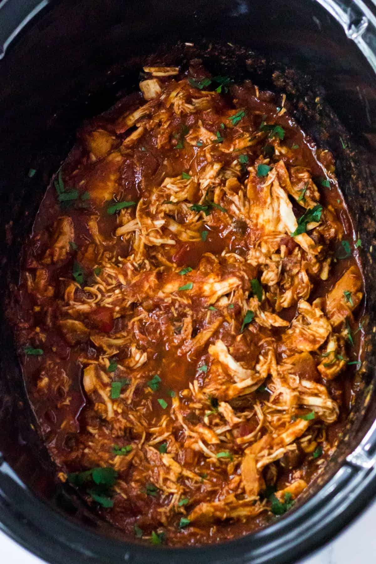 Slow cooker salsa chicken shredded in the bowl of a crockpot.