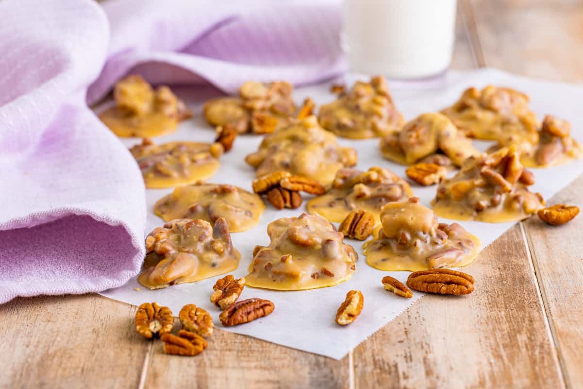 Several buttery pecan pralines with a glass of milk.