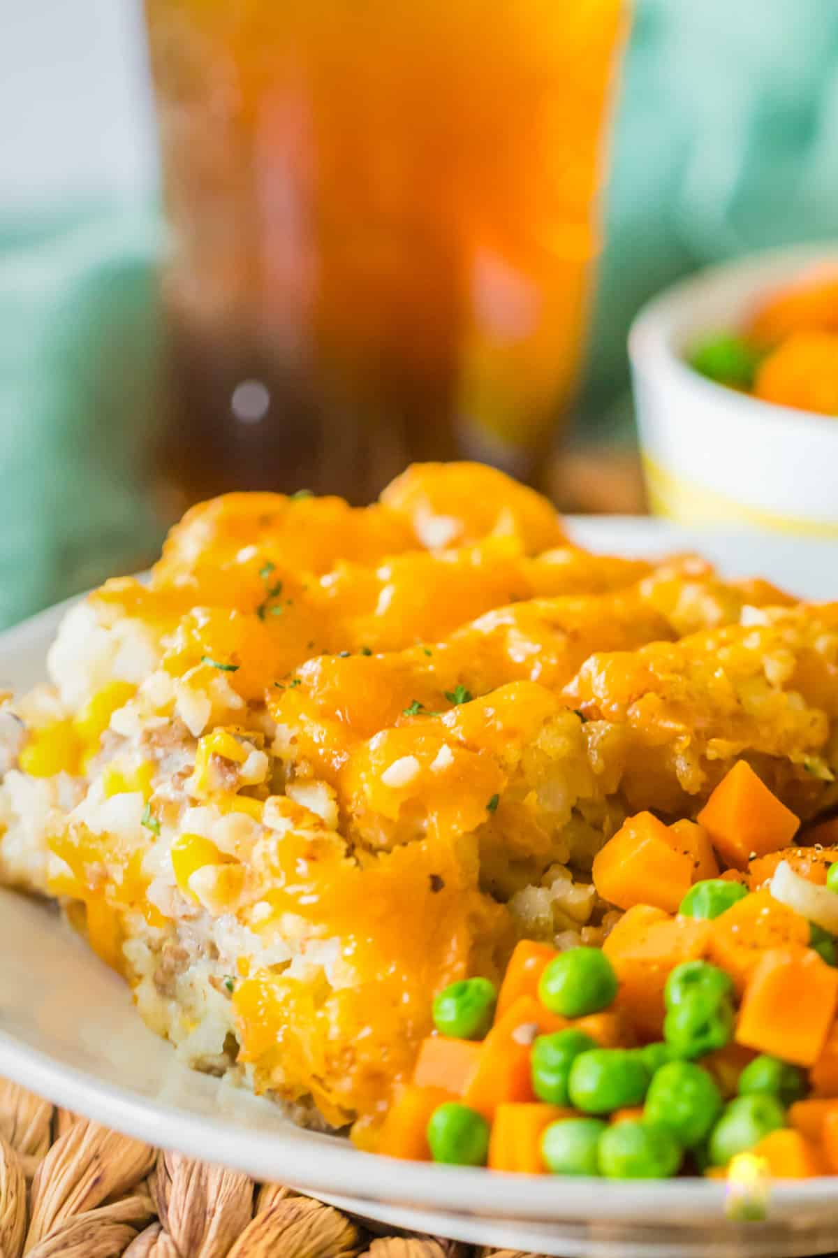 Plated portion of crock pot tater tot hot dish with veggies and iced tea.